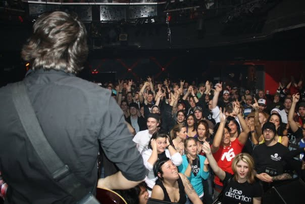 Vue d’une salle comble derrière un guitariste de Turbo Distortion sur scène